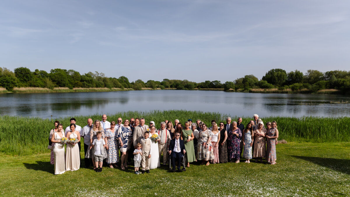 Wedding group photo on the lakeside lawn at De Vere Cotswold Water Park, Gloucestershire