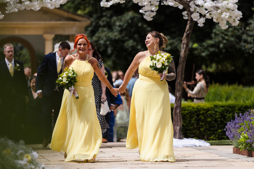 Bridesmaids in yellow dresses laughing after the ceremony at Rowton Castle — candid moment in the castle gardens